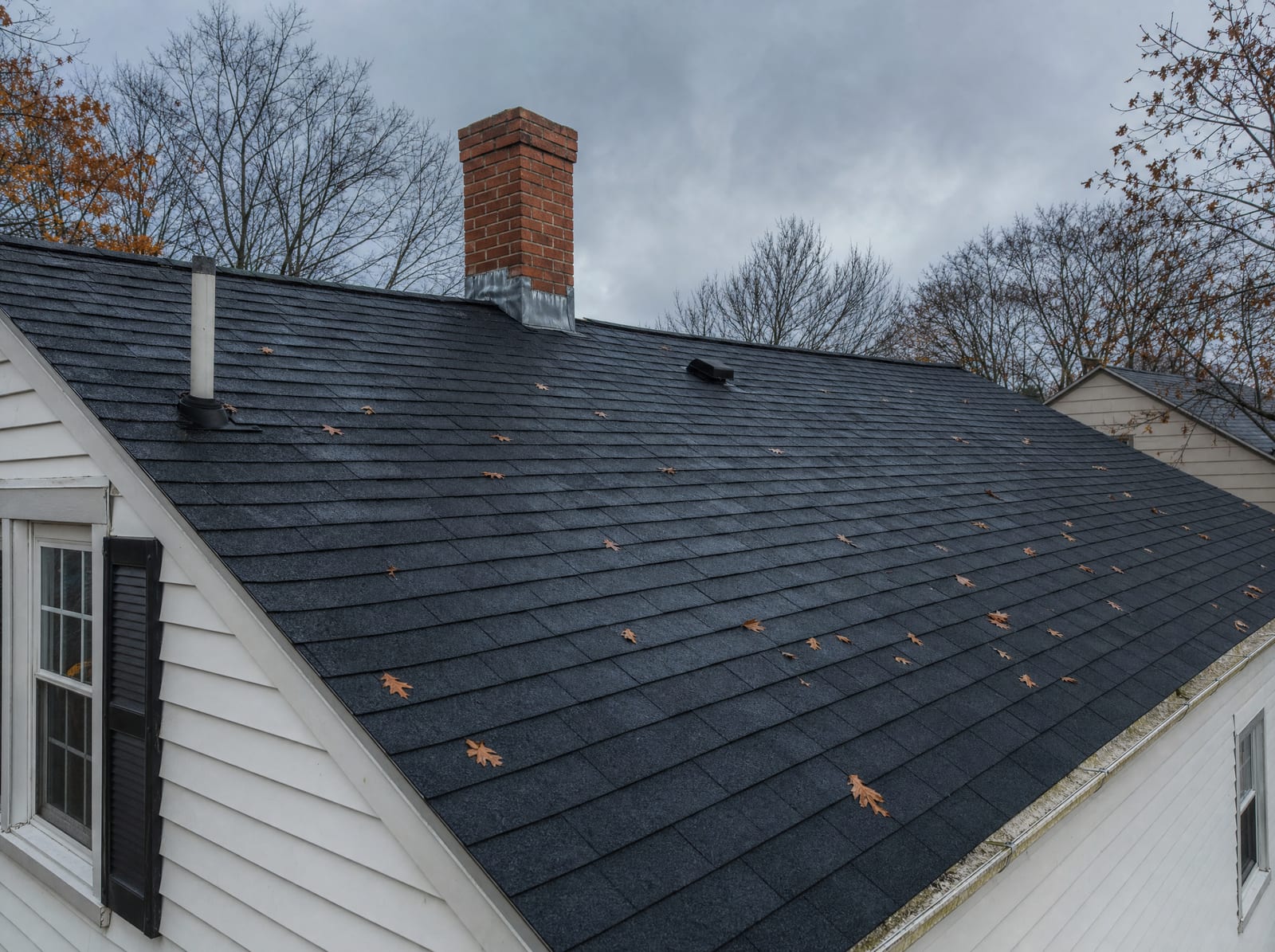 Weathered asphalt shingle roof on a Connecticut colonial under an overcast autumn sky
