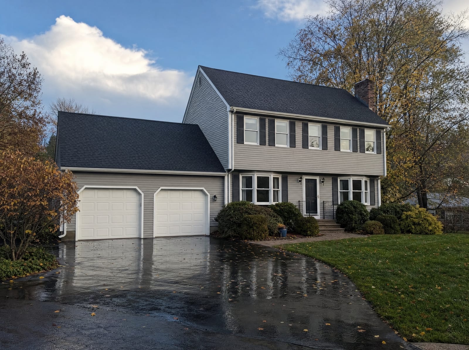 Completed new asphalt shingle roof on a Connecticut home under a clearing post-storm sky