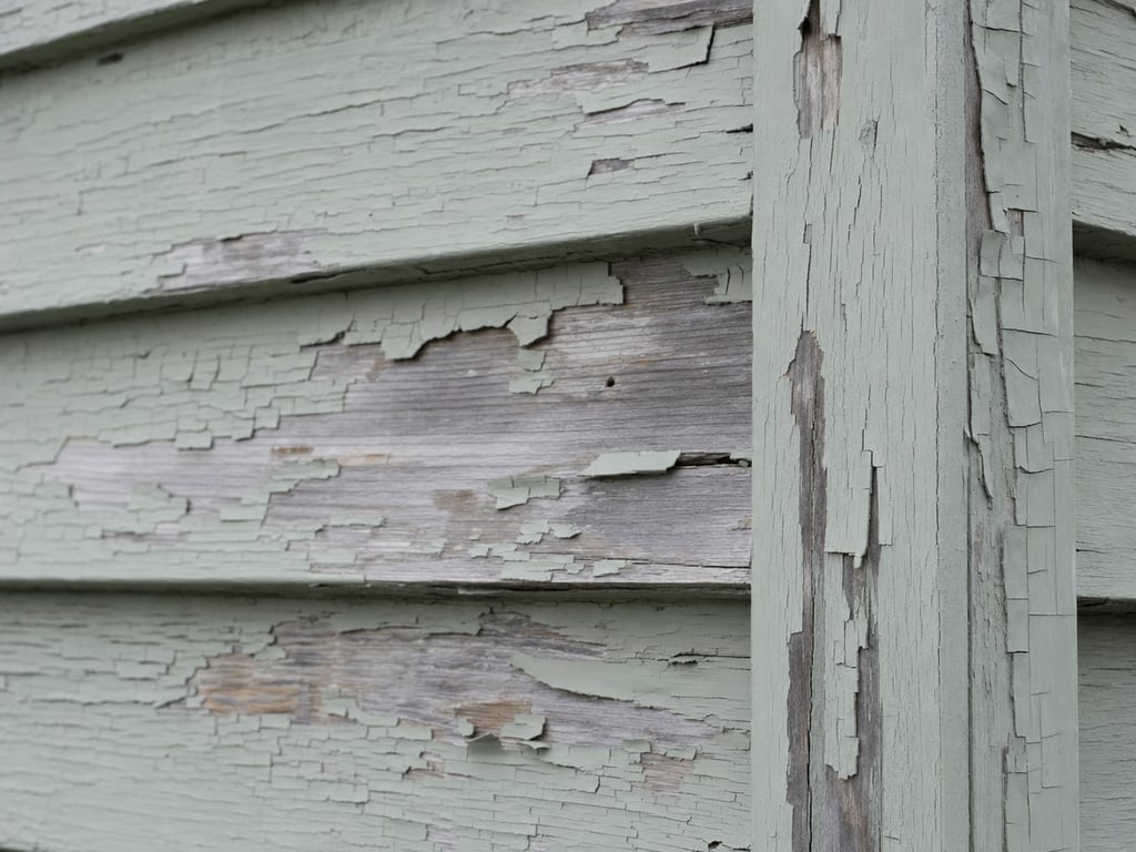 Peeling and chalking exterior paint on weathered wood clapboard and trim