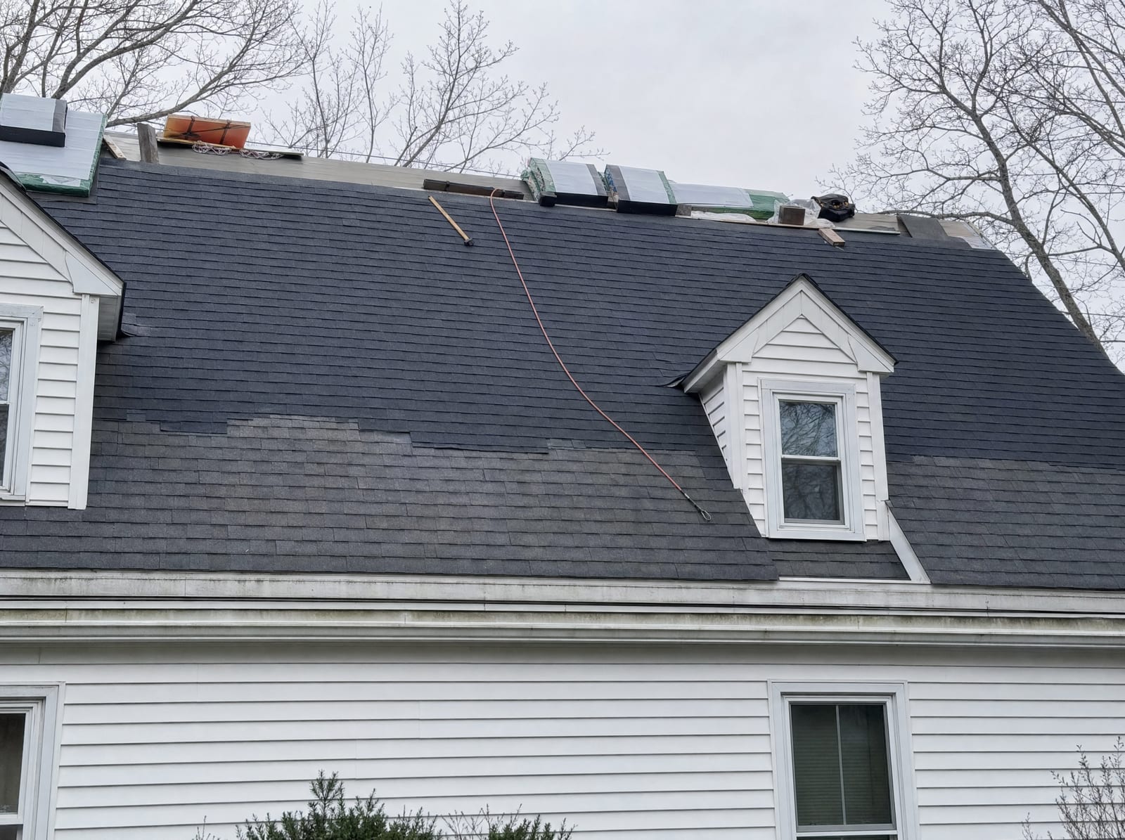 New shingles being laid directly over an old layer, the boundary between new and old visible