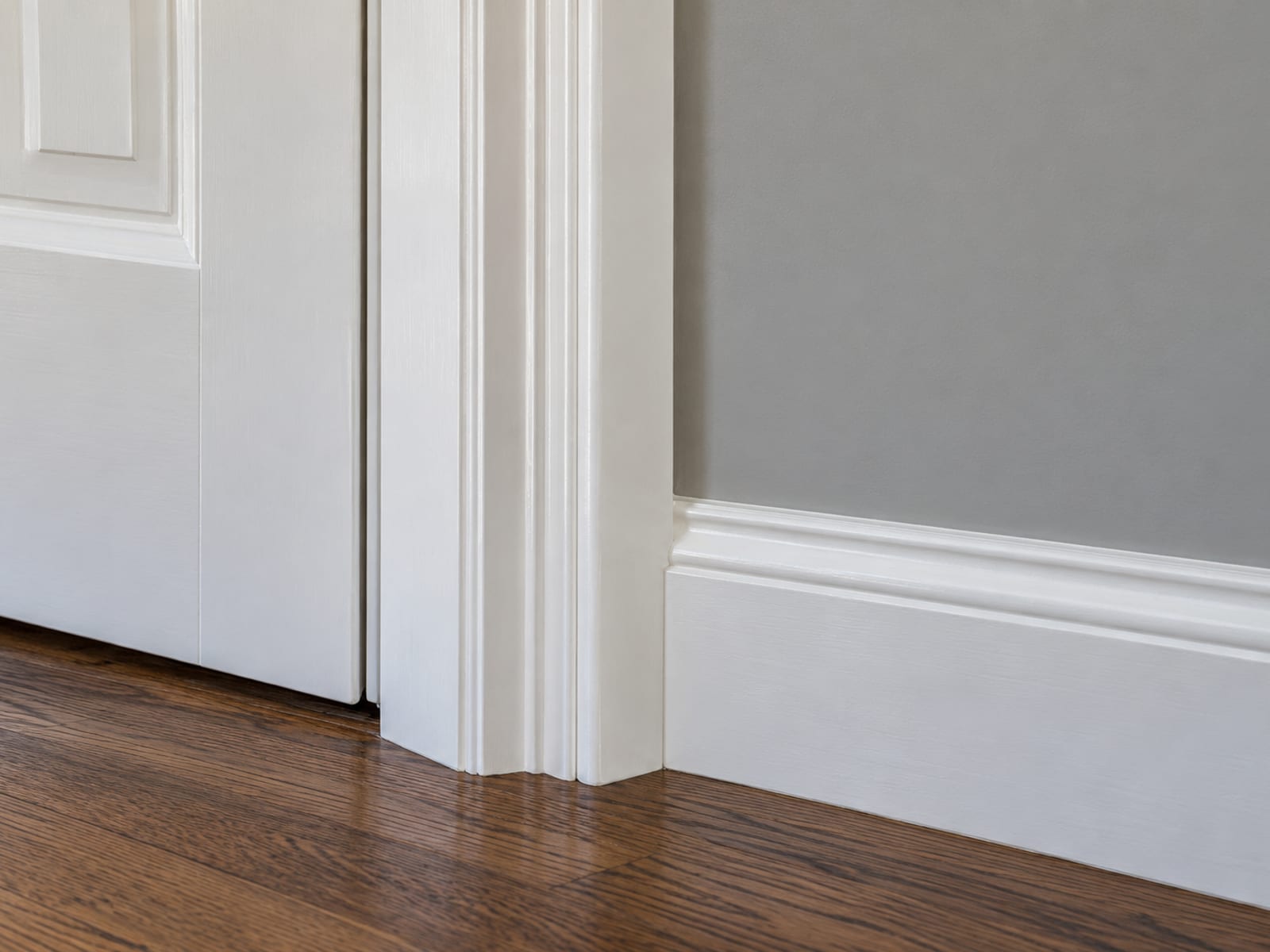 Close detail of a door casing with crisp white paint meeting a smooth primed and painted wall at a clean line