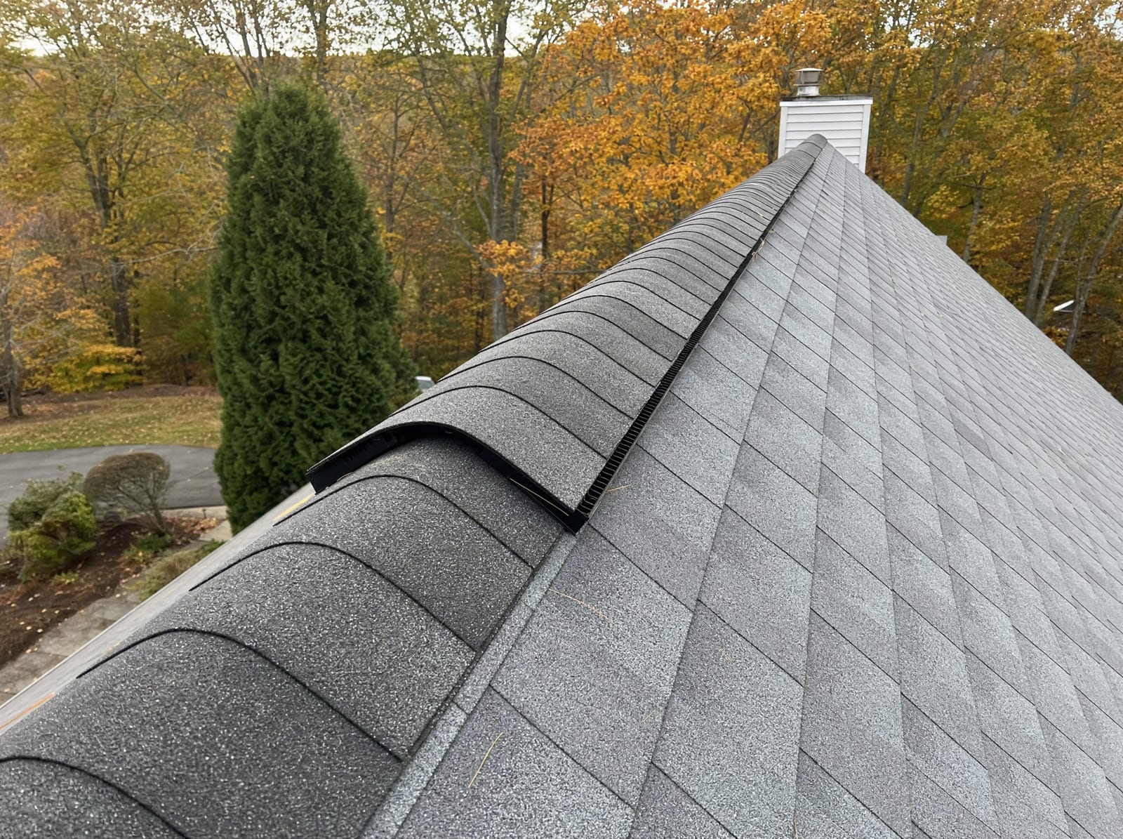 Ridge vent and ridge cap being installed along the peak of a steep-pitch roof