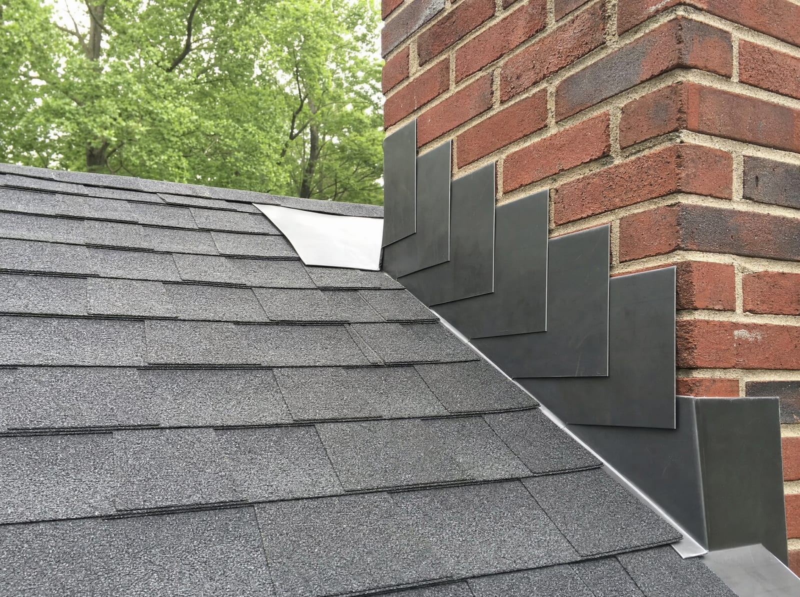 Step-flashing installed where the roof meets a brick chimney