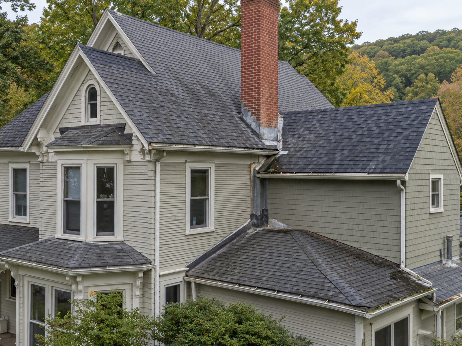 Older Victorian house with mixed rooflines, an addition, a brick chimney and patched flashing