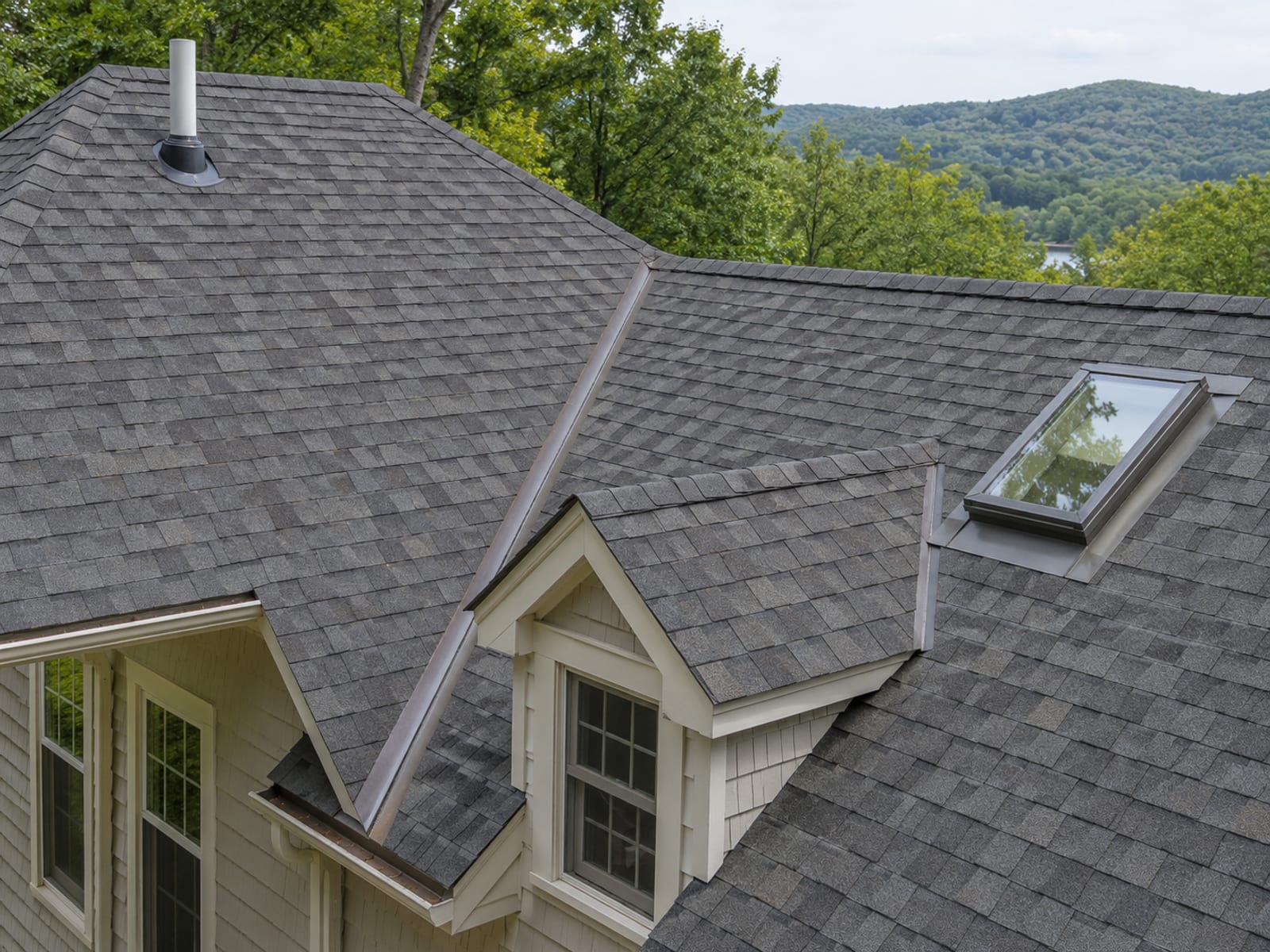 Steep shingle roof showing a plumbing vent pipe boot, a valley and a skylight in one view