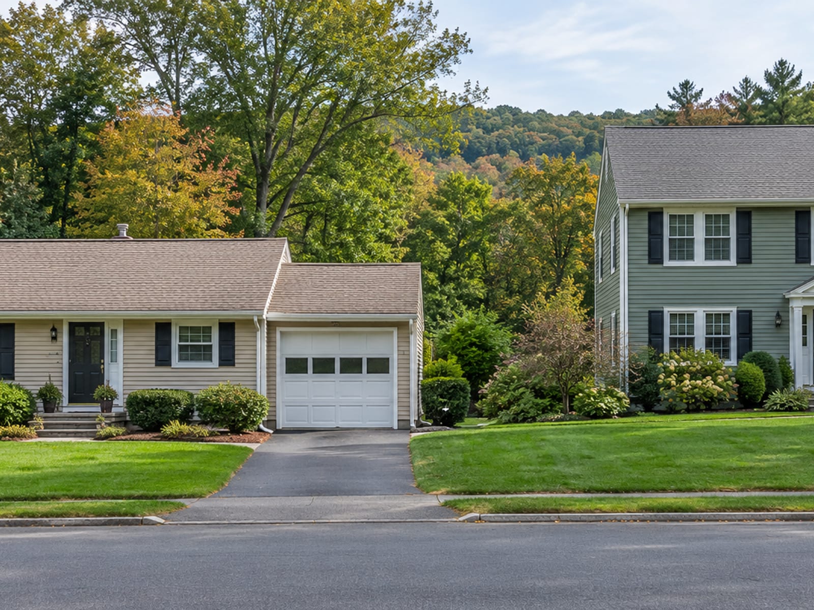 Two neighboring houses on a Connecticut street, a tan vinyl ranch and a sage green fiber cement colonial, both with finished siding