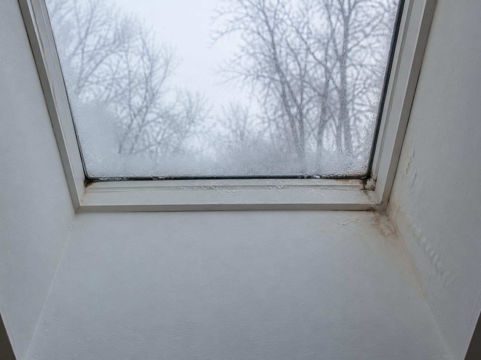 Interior skylight with fogged glass and a faint water stain on the painted drywall corner of its light shaft