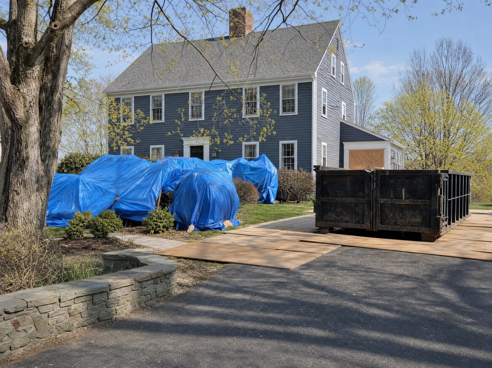Day-one roofing prep: landscaping tarped and a dumpster staged in the driveway