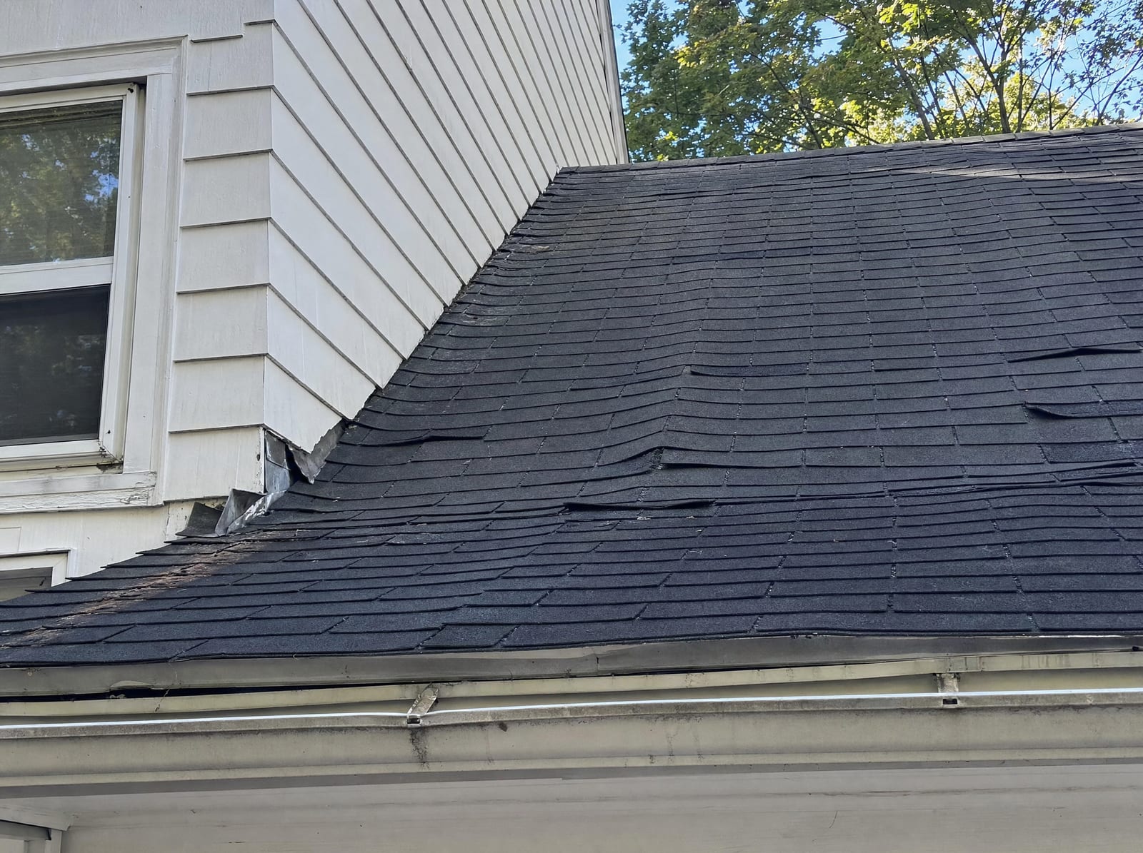 Poorly installed roof with buckled shingles and sloppy flashing