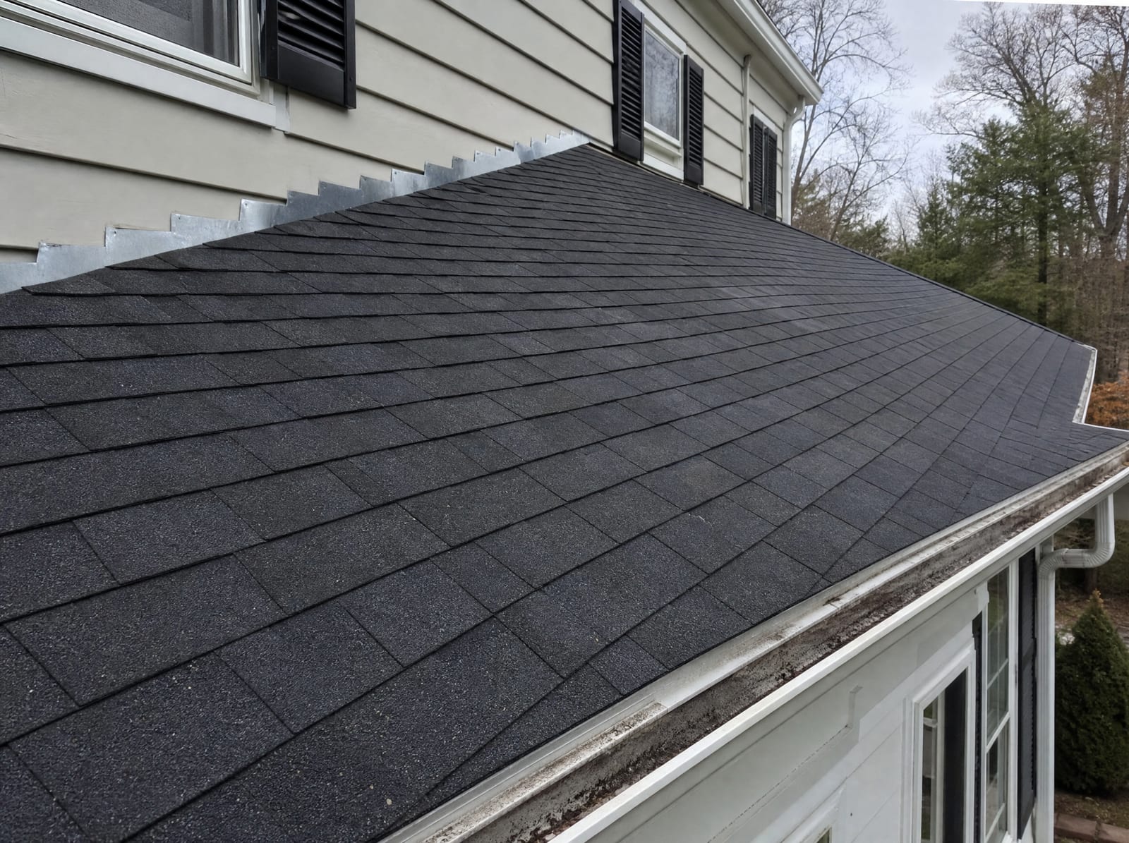 Freshly completed dark architectural asphalt shingle roof on a Cheshire colonial home with new step flashing and a ridge vent