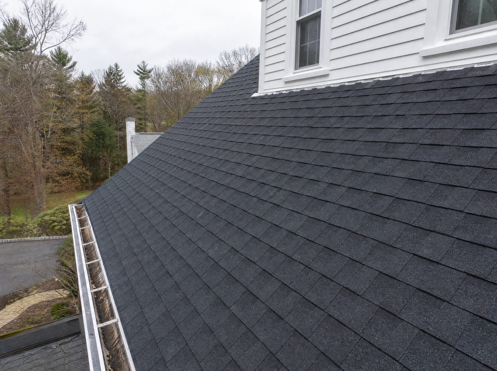 Freshly completed dark architectural asphalt shingle roof on a Middlebury colonial home with new step flashing and a ridge vent