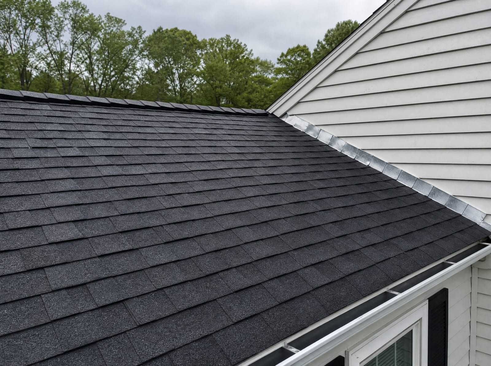 Freshly completed dark architectural asphalt shingle roof on a Oxford colonial home with new step flashing and a ridge vent