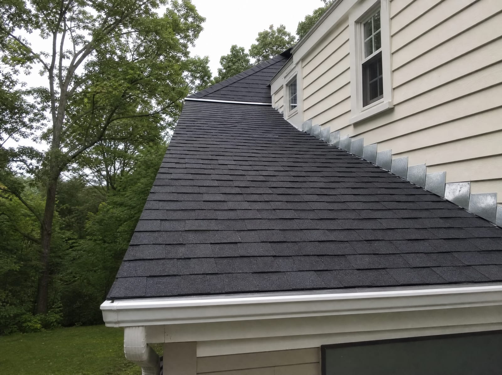 Freshly completed dark architectural asphalt shingle roof on a Wallingford colonial home with new step flashing and a ridge vent
