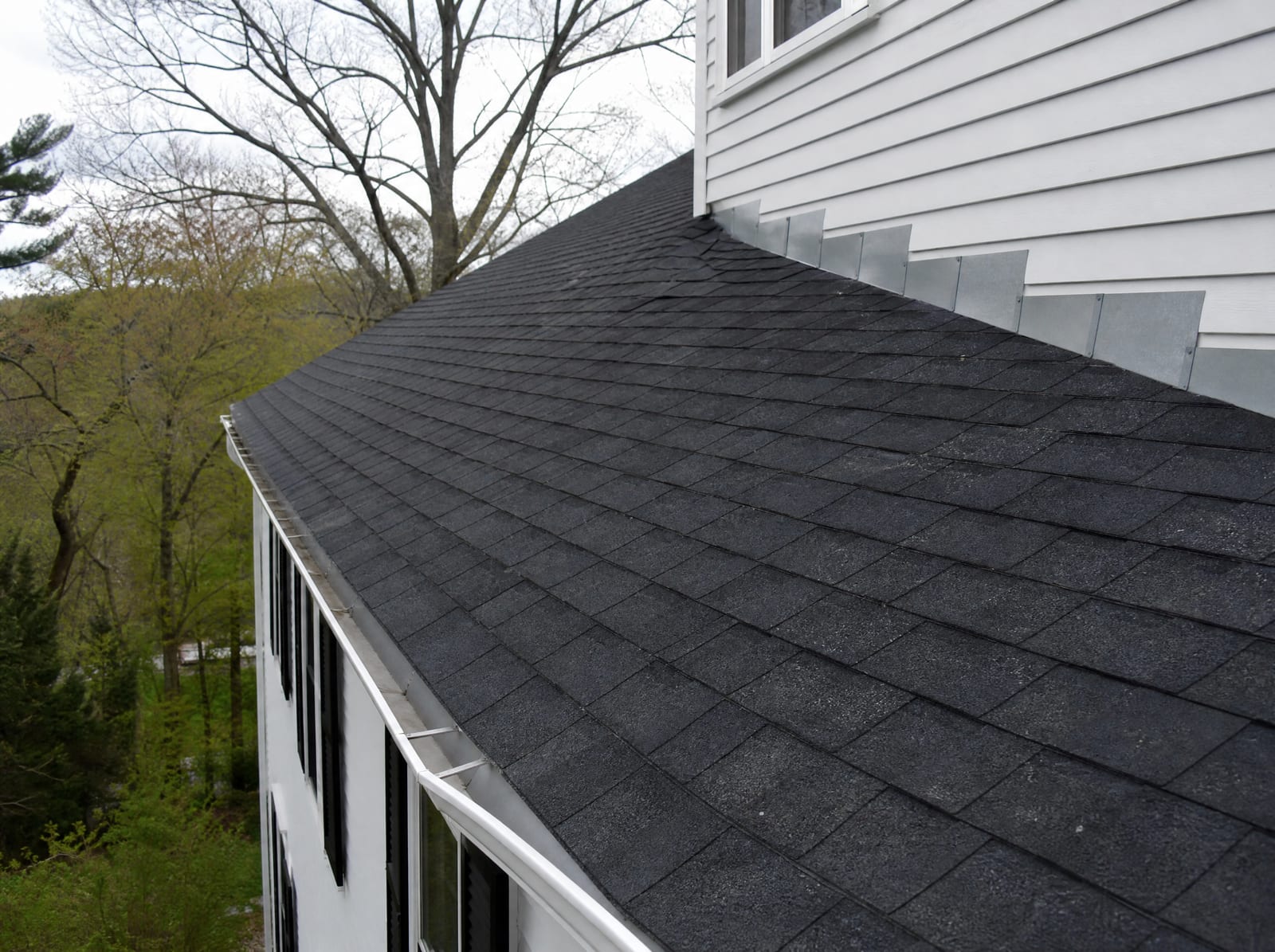 Freshly completed dark architectural asphalt shingle roof on a historic Woodbury colonial home with new step flashing and a ridge vent